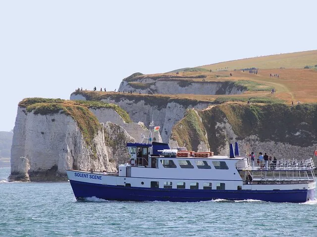 Ausflugsboot bei der Fahrt vorbei an weißen Kreidefelsen der Jurassic Coast in England
