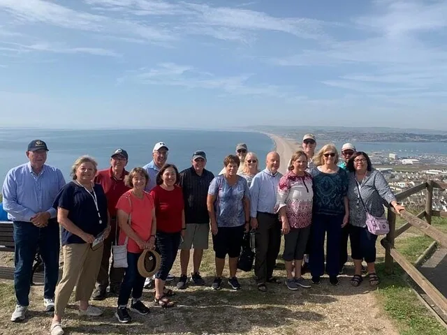 Groupe de touristes posant sur une colline surplombant Chesil Beach sur la Côte jurassique