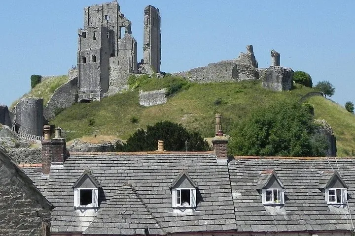 Historic castle ruins sitting on a hill behind slate roofed houses.