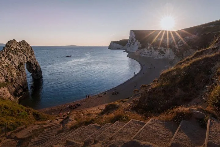 Sun setting over Durdle Door beach, viewed from steps leading down.