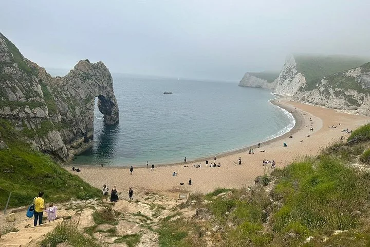 Personas bajando escaleras hacia Durdle Door y la playa de arena de abajo