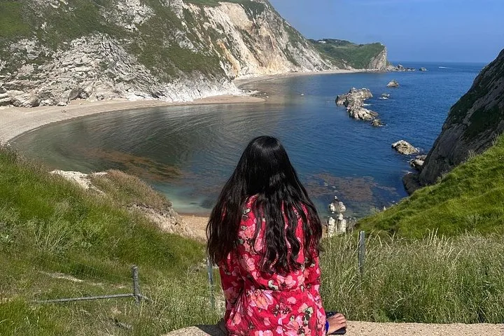 Mujer con vestido floreado sentada en una colina con vistas a Man O'War Beach
