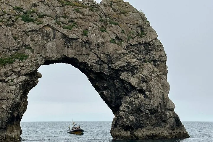 Small boat passing through the iconic rocky archway of Durdle Door
